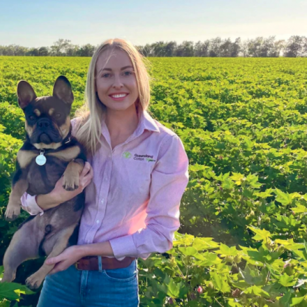 Cotton marketer Jess Strauch pictured holding her dog standing in a cotton paddock.