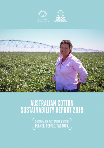 Cotton grower standing in a field with a lateral move irrigator in the distance.